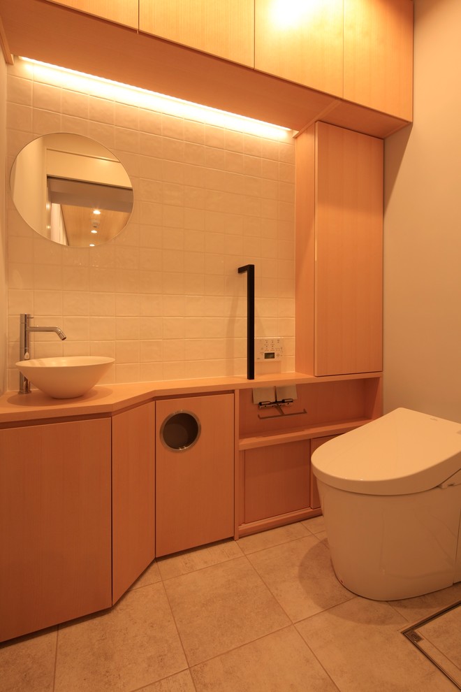 Cette image montre un petit WC et toilettes asiatique avec un placard en trompe-l'oeil, des portes de placard marrons, WC à poser, un carrelage multicolore, des carreaux de porcelaine, un mur blanc, un sol en carrelage de porcelaine, un lavabo intégré, un plan de toilette en surface solide et un sol gris.