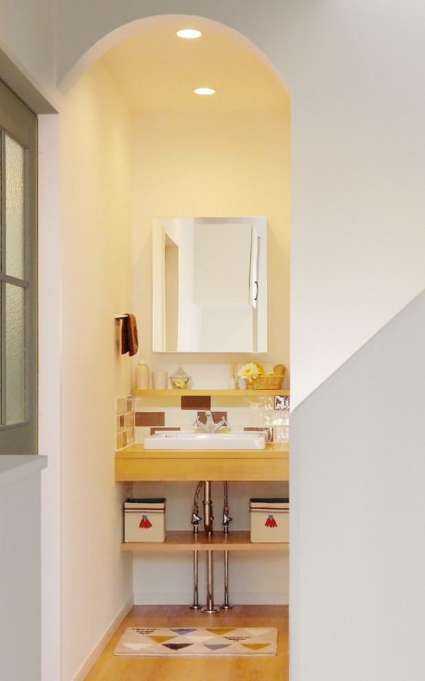 Esempio di un bagno di servizio con ante di vetro, piastrelle in terracotta, pareti bianche, pavimento in compensato, lavabo a bacinella e pavimento beige