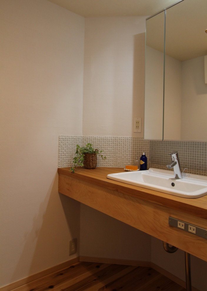 Idées déco pour un petit WC et toilettes moderne avec un carrelage blanc, des carreaux de béton, un mur blanc, un sol en bois brun, un lavabo posé, un plan de toilette en bois et un plan de toilette marron.