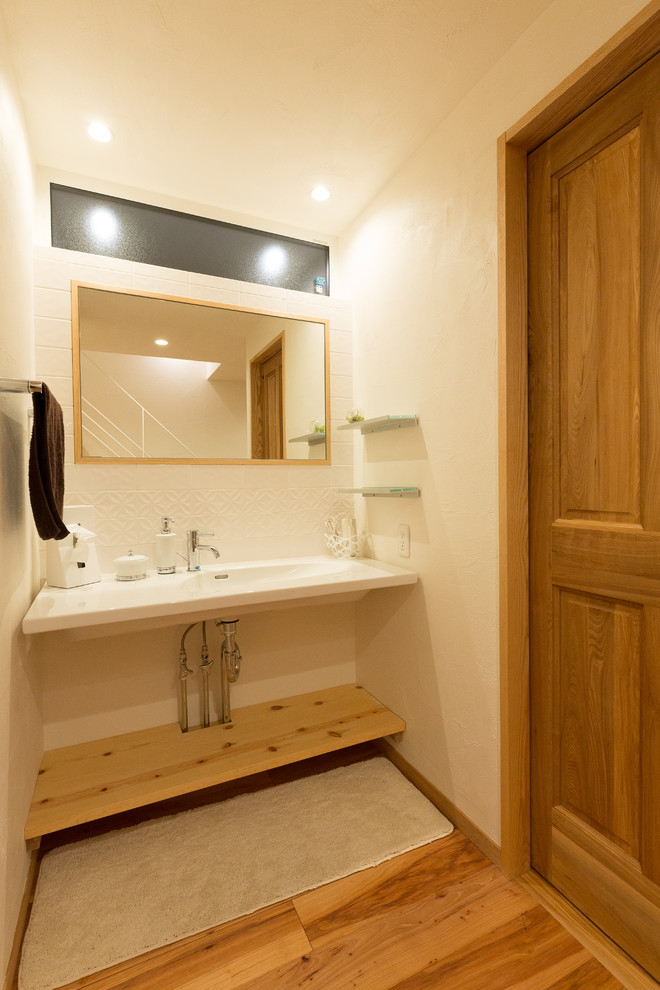 Foto di un bagno di servizio minimalista con piastrelle bianche, pavimento in legno massello medio e pavimento marrone
