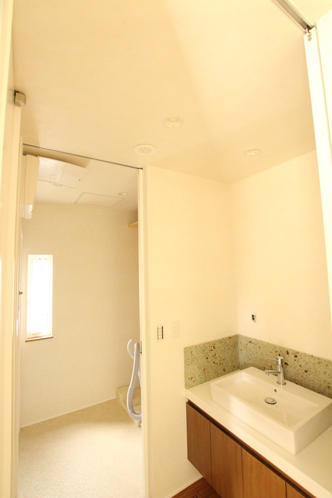 Moderne Gästetoilette mit Lamellenschränken, hellbraunen Holzschränken, grünen Fliesen, weißer Waschtischplatte und schwebendem Waschtisch in Sonstige