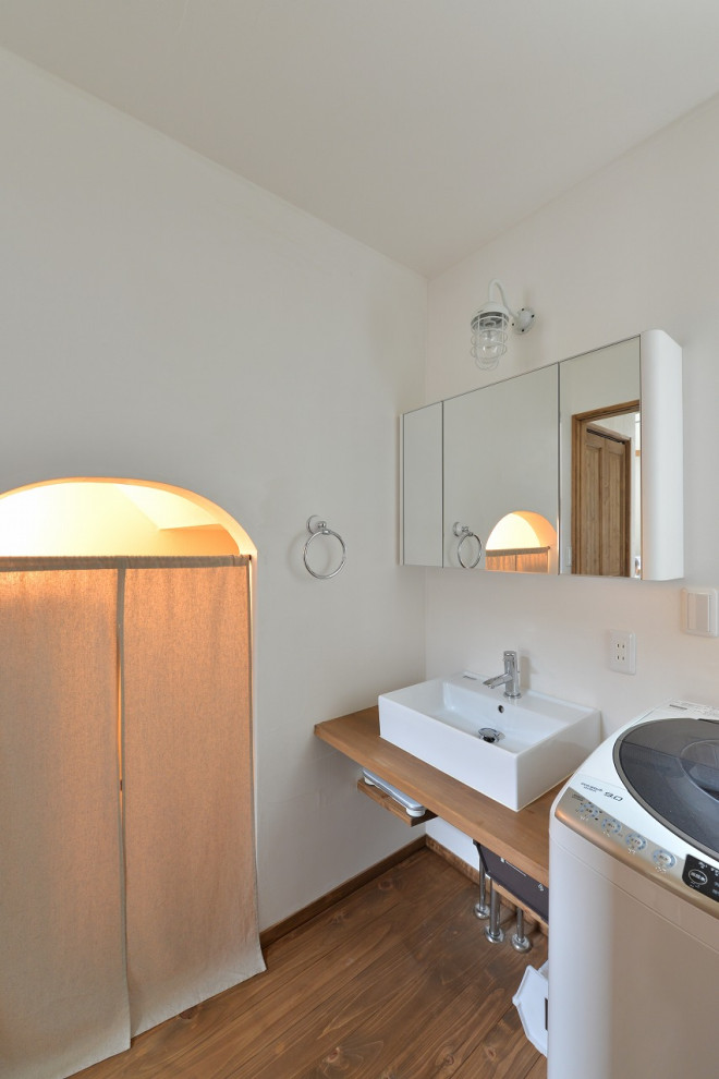 Inspiration för ett mellanstort skandinaviskt brun brunt toalett, med öppna hyllor, bruna skåp, en toalettstol med hel cisternkåpa, vita väggar, mellanmörkt trägolv, ett fristående handfat, träbänkskiva och brunt golv