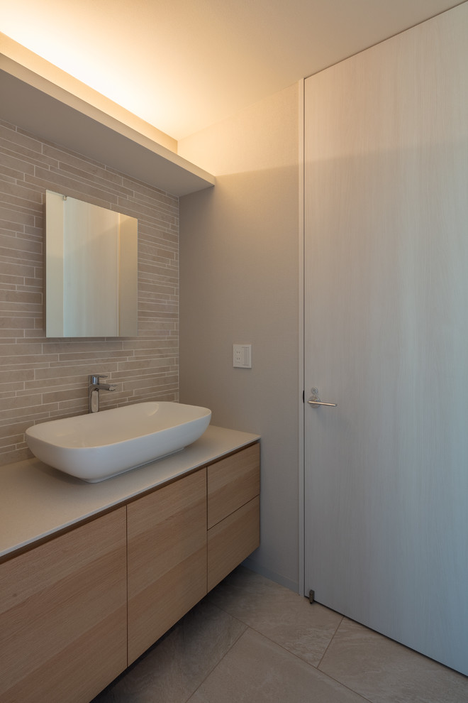 Стильный дизайн: туалет в стиле модернизм с бежевой плиткой, серыми стенами, настольной раковиной, столешницей из искусственного камня, бежевым полом и белой столешницей - последний тренд
