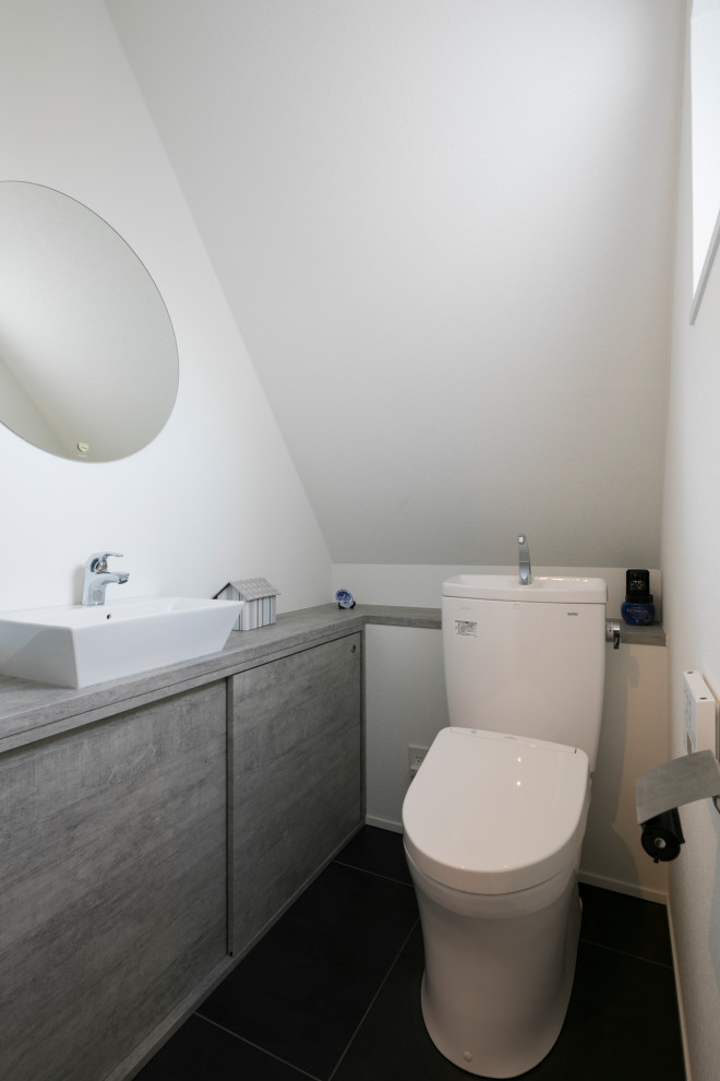 Cette photo montre un petit WC et toilettes asiatique avec un placard à porte affleurante, un mur blanc, un sol gris, des portes de placard grises, WC séparés, un sol en vinyl, une vasque et un plan de toilette gris.