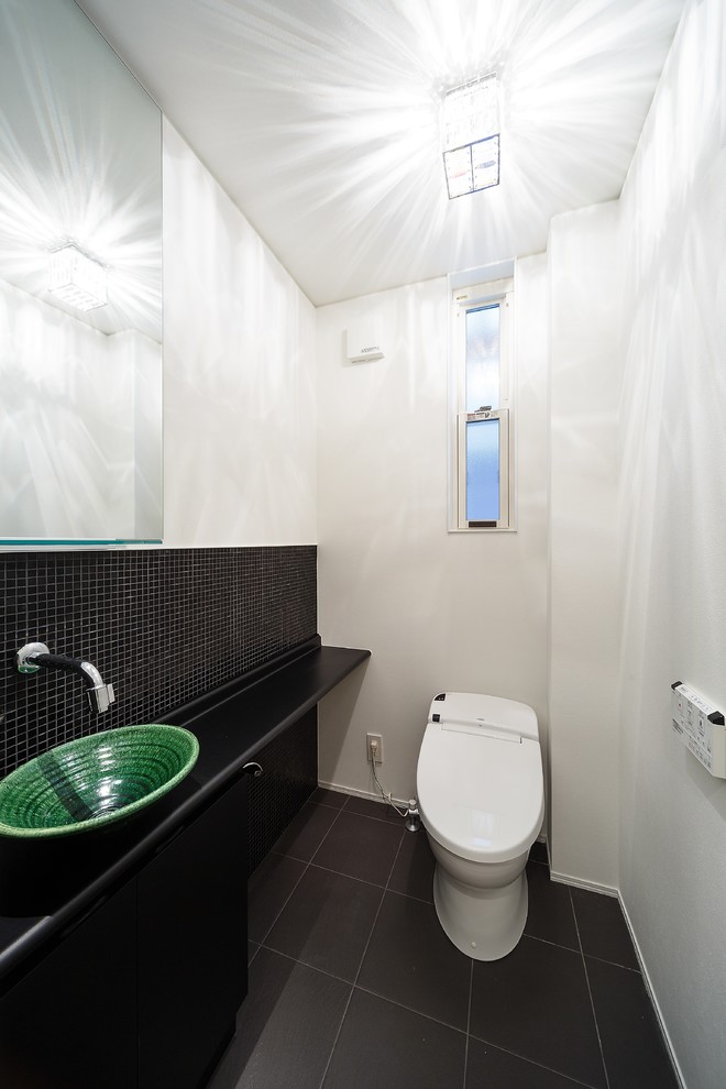 Ispirazione per un bagno di servizio minimal con ante lisce, pareti bianche, lavabo a bacinella e pavimento nero