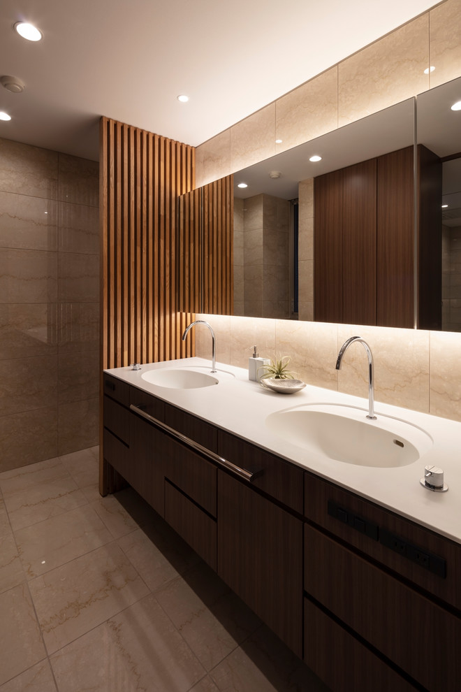 Moderne Gästetoilette mit flächenbündigen Schrankfronten, dunklen Holzschränken, beiger Wandfarbe, Marmorboden, integriertem Waschbecken und beigem Boden in Osaka