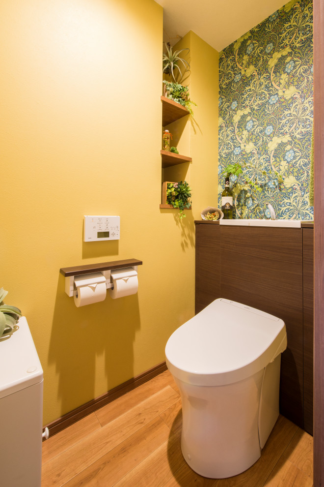 На фото: туалет среднего размера с желтыми стенами, полом из мозаичной плитки и коричневым полом с