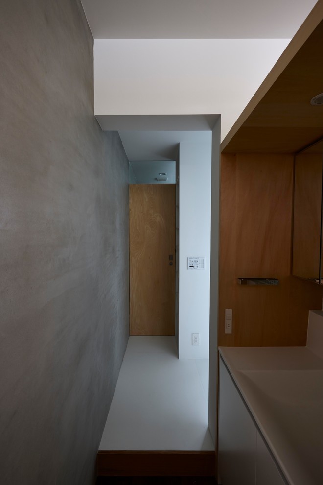 Réalisation d'un petit WC et toilettes nordique avec un placard à porte affleurante, des portes de placard blanches, un carrelage blanc, un sol en vinyl, un plan de toilette en surface solide et un sol blanc.