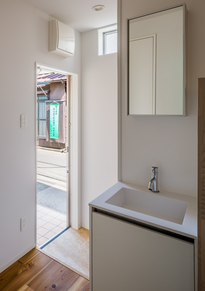 Medium sized scandinavian cloakroom in Other with beaded cabinets, white cabinets, white tiles, ceramic tiles, white walls, light hardwood flooring, an integrated sink, solid surface worktops, beige floors and a built in vanity unit.