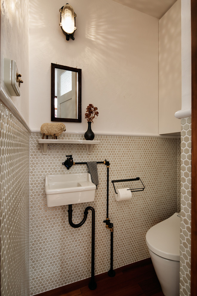 Imagen de aseo industrial pequeño con sanitario de una pieza, baldosas y/o azulejos en mosaico, paredes blancas, lavabo suspendido y baldosas y/o azulejos beige