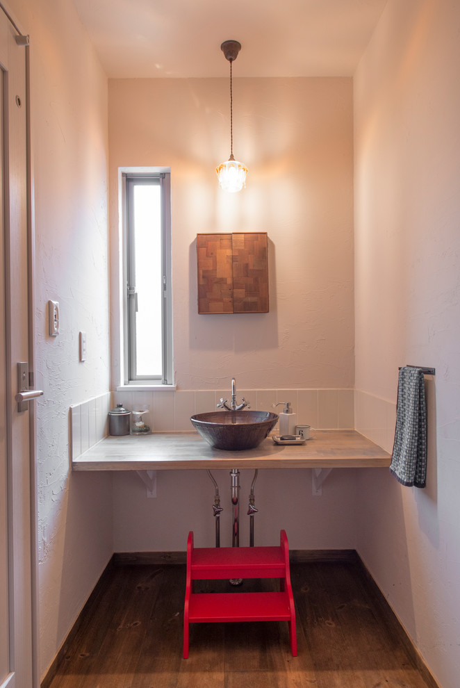 Immagine di un bagno di servizio etnico con pareti bianche, pavimento in legno massello medio, lavabo a bacinella e pavimento marrone