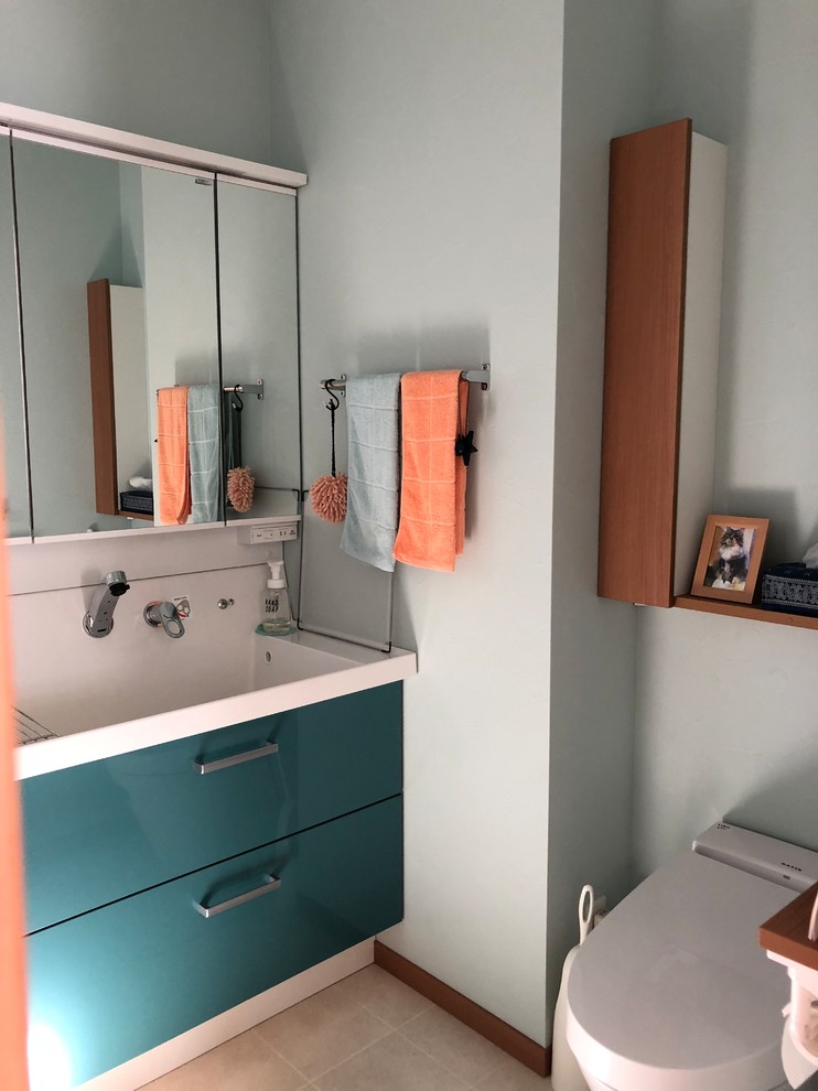 Aménagement d'un petit WC et toilettes contemporain avec des portes de placard turquoises, WC à poser et un lavabo intégré.