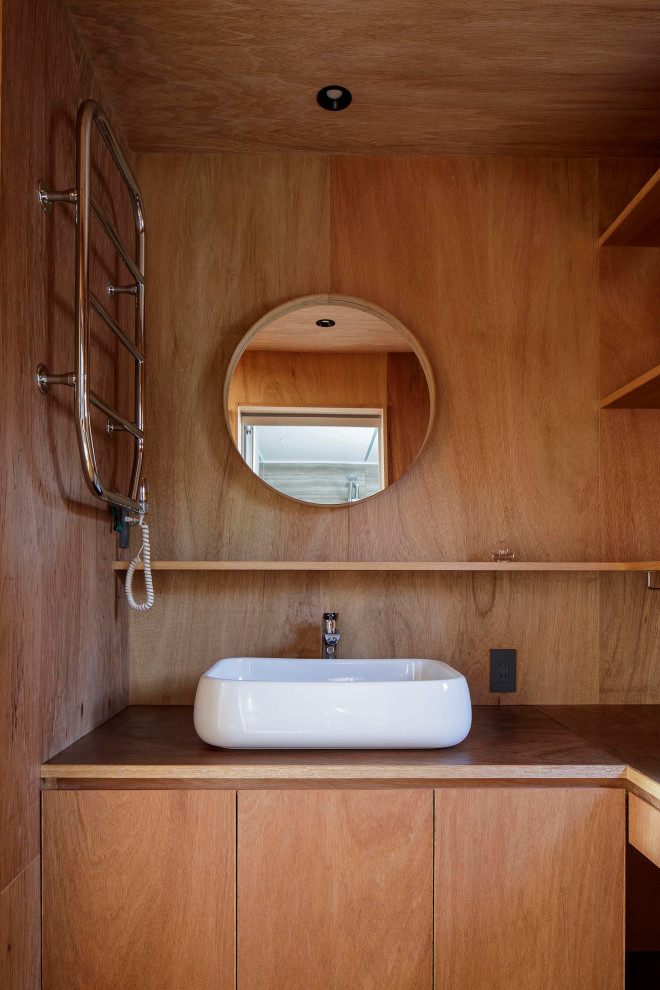 Modern inredning av ett litet brun brunt toalett, med luckor med profilerade fronter, bruna skåp, bruna väggar, plywoodgolv, ett nedsänkt handfat, träbänkskiva och brunt golv