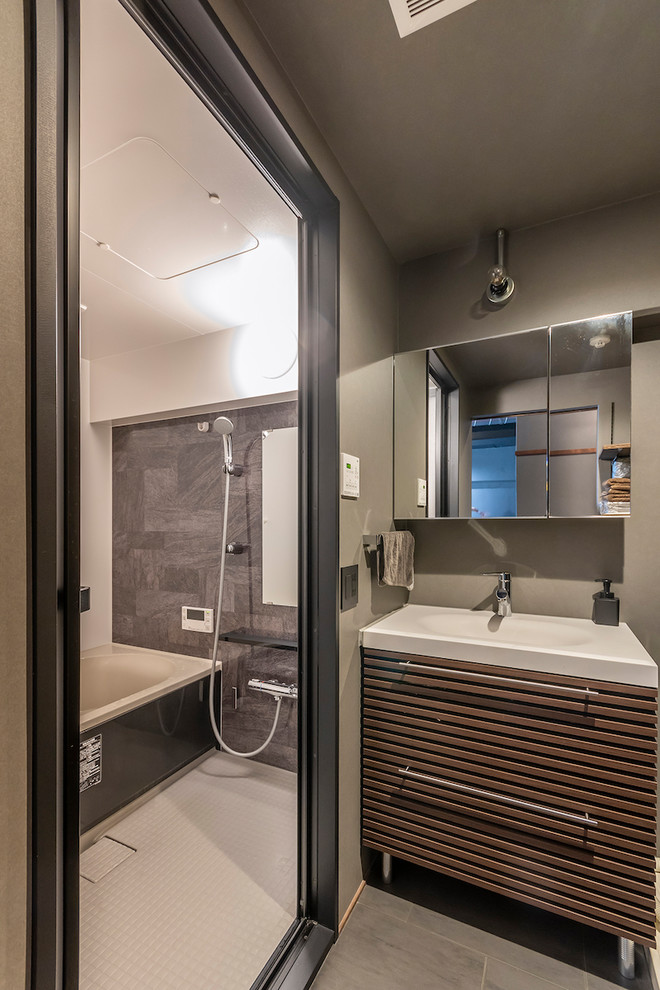 Diseño de cuarto de baño urbano con puertas de armario de madera oscura, paredes grises, lavabo integrado, suelo gris y armarios con paneles lisos