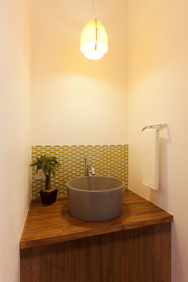 Ispirazione per un bagno di servizio etnico con ante lisce, ante marroni, pareti bianche, lavabo a bacinella, top in legno e top marrone