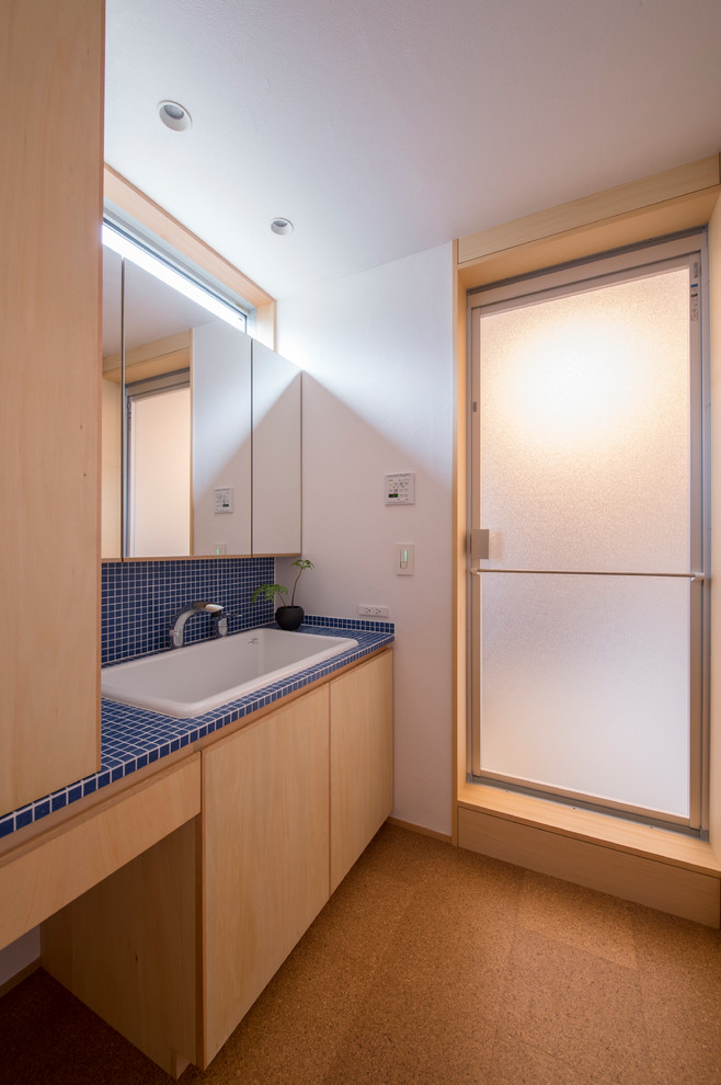 横浜にある和風のおしゃれなトイレ・洗面所 (青いタイル、オーバーカウンターシンク、青い洗面カウンター、磁器タイル、コルクフローリング、タイルの洗面台、白い壁、茶色い床) の写真