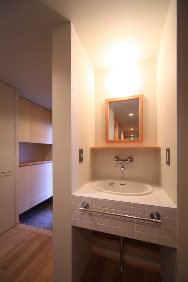 Exempel på ett rustikt vit vitt toalett, med öppna hyllor, vita skåp, vit kakel, porslinskakel, vita väggar, mellanmörkt trägolv, ett nedsänkt handfat, kaklad bänkskiva och beiget golv