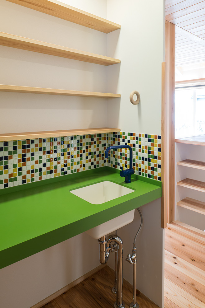 Inspiration for a world-inspired cloakroom in Tokyo Suburbs with open cabinets, light wood cabinets, multi-coloured tiles, mosaic tiles, white walls, light hardwood flooring, a submerged sink, beige floors and green worktops.