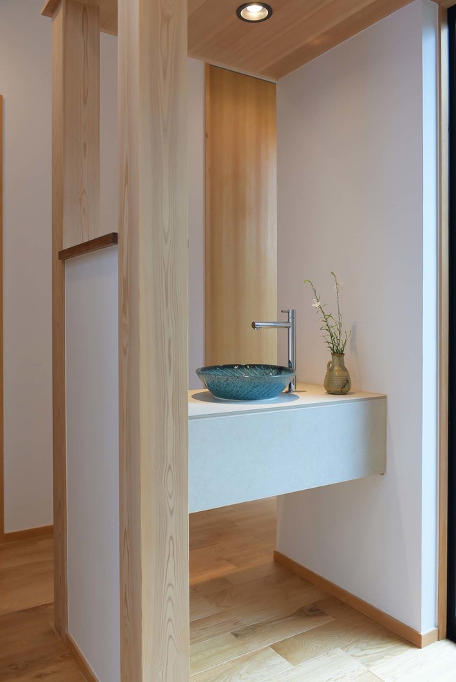 Foto på ett funkis grå toalett, med vita väggar, ljust trägolv, ett fristående handfat och beiget golv