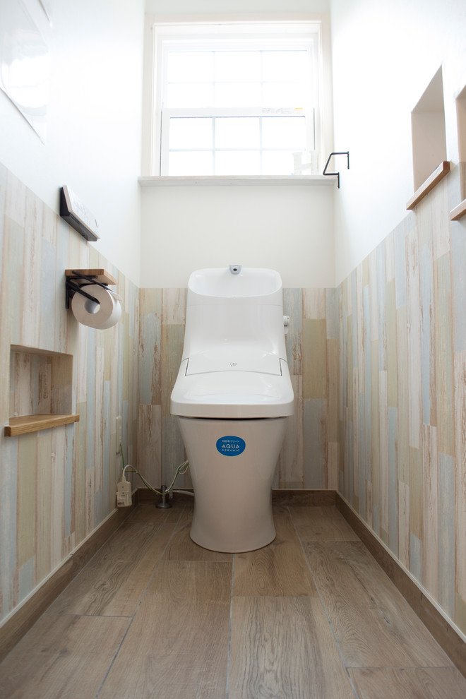 Cette image montre un WC et toilettes marin avec un mur blanc, parquet peint et un sol gris.
