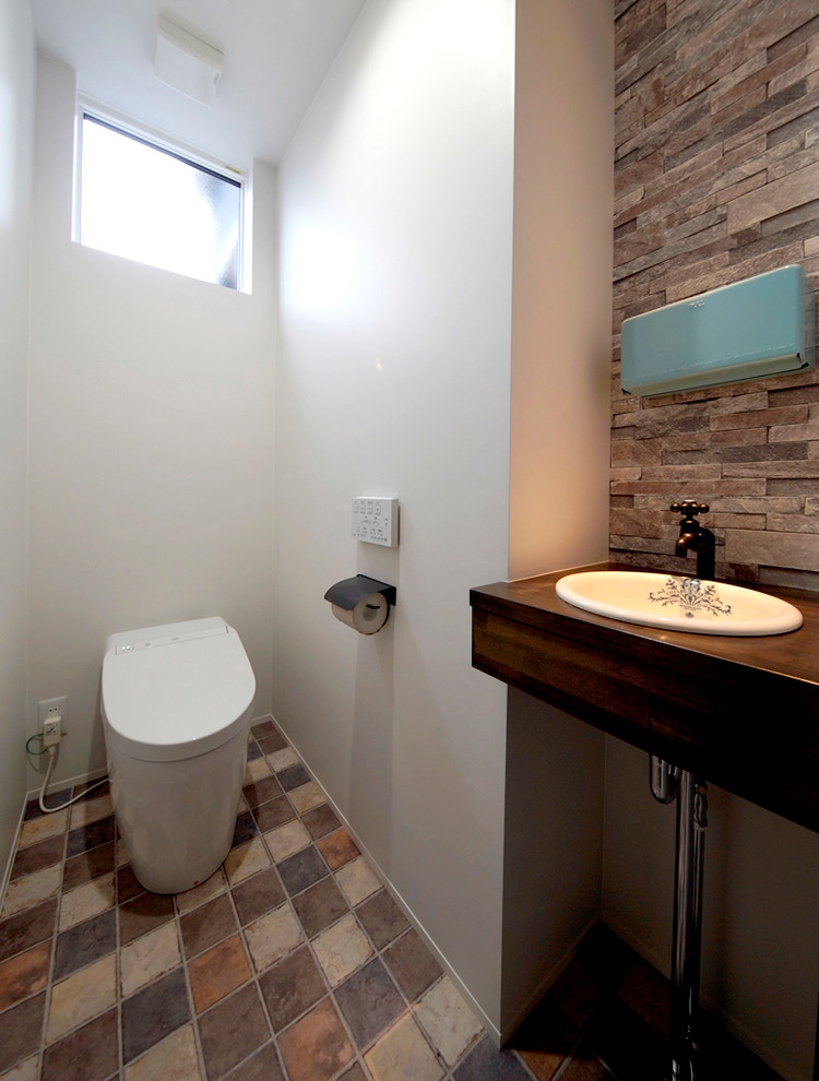 他の地域にあるモダンスタイルのおしゃれなトイレ・洗面所 (白い壁、オーバーカウンターシンク、茶色い床) の写真