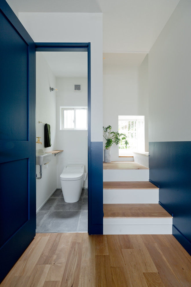 Foto de aseo contemporáneo con paredes azules, suelo de cemento, lavabo suspendido y suelo gris