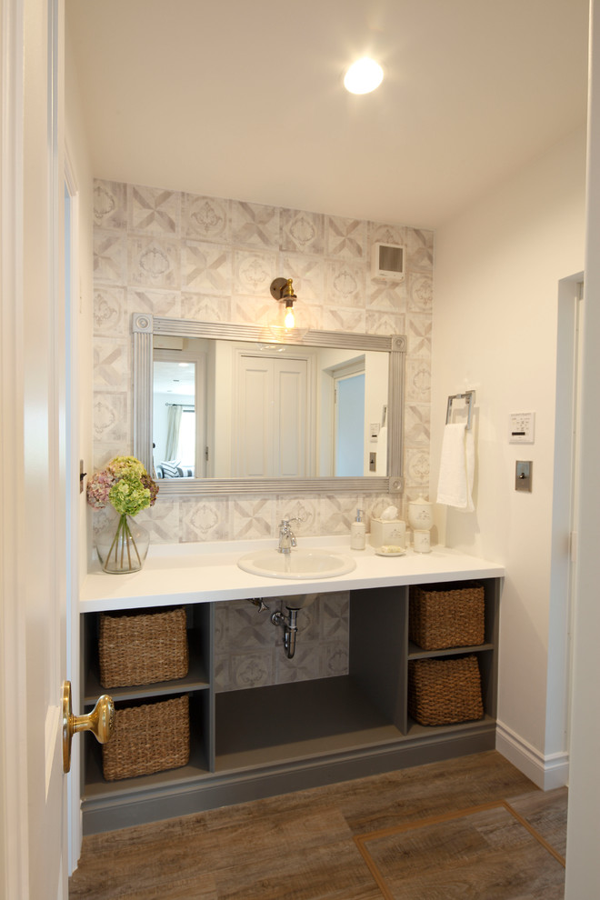 Klassisk inredning av ett toalett, med vita väggar, mörkt trägolv, ett nedsänkt handfat, brunt golv, öppna hyllor och grå skåp