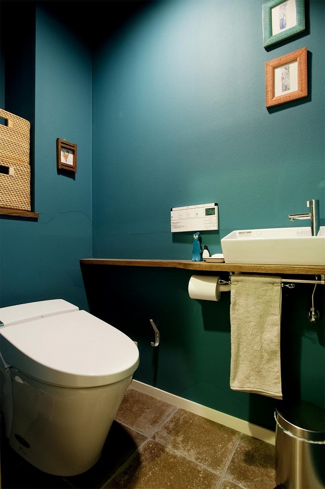 На фото: туалет в стиле фьюжн с синими стенами, настольной раковиной, столешницей из дерева, коричневым полом и коричневой столешницей