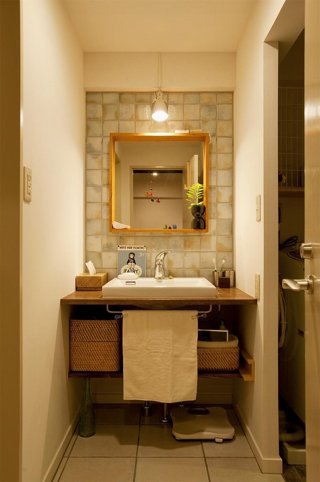 Réalisation d'un WC et toilettes bohème avec un placard sans porte, des portes de placard marrons, un mur blanc, une vasque, un plan de toilette en bois, un sol gris et un plan de toilette marron.