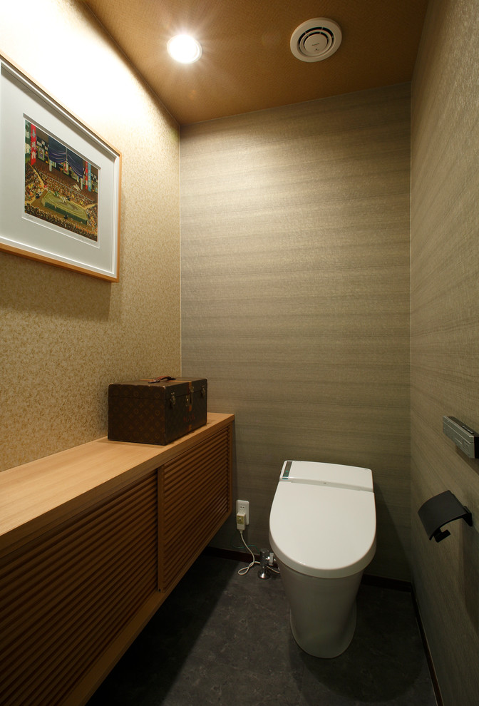 Пример оригинального дизайна: туалет среднего размера в восточном стиле с фасадами островного типа, светлыми деревянными фасадами, унитазом-моноблоком, коричневыми стенами, полом из винила, столешницей из дерева и серым полом