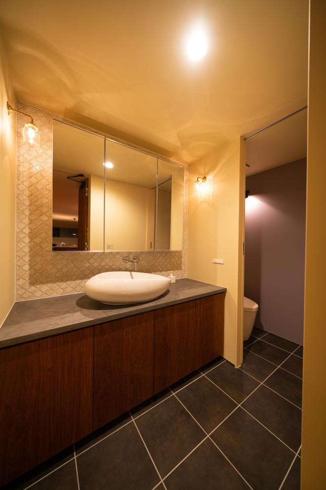На фото: туалет в стиле ретро с темными деревянными фасадами, унитазом-моноблоком, белой плиткой, бежевыми стенами, полом из мозаичной плитки, консольной раковиной, серым полом и серой столешницей с