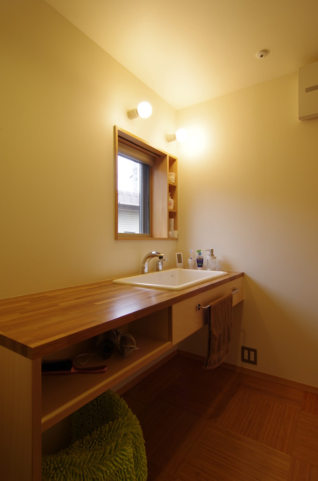 他の地域にあるモダンスタイルのおしゃれなトイレ・洗面所 (オープンシェルフ、白い壁、オーバーカウンターシンク、木製洗面台、淡色木目調キャビネット) の写真