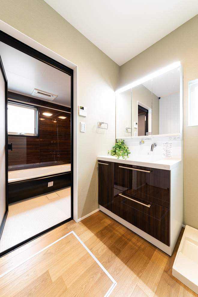 Idées déco pour un WC et toilettes moderne avec un placard à porte plane, des portes de placard marrons, un mur gris, un sol en bois brun, un lavabo intégré et un sol marron.
