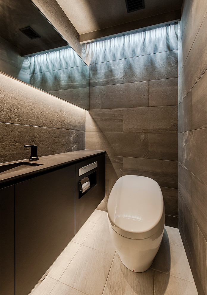 Foto på ett funkis svart toalett, med svarta skåp, grå kakel, grå väggar, ett undermonterad handfat och beiget golv