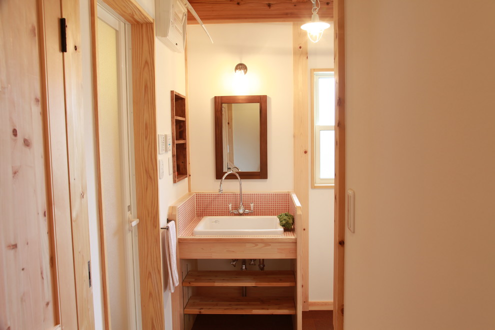他の地域にあるカントリー風のおしゃれなトイレ・洗面所 (ピンクのタイル、白い壁、コルクフローリング、アンダーカウンター洗面器、茶色い床) の写真