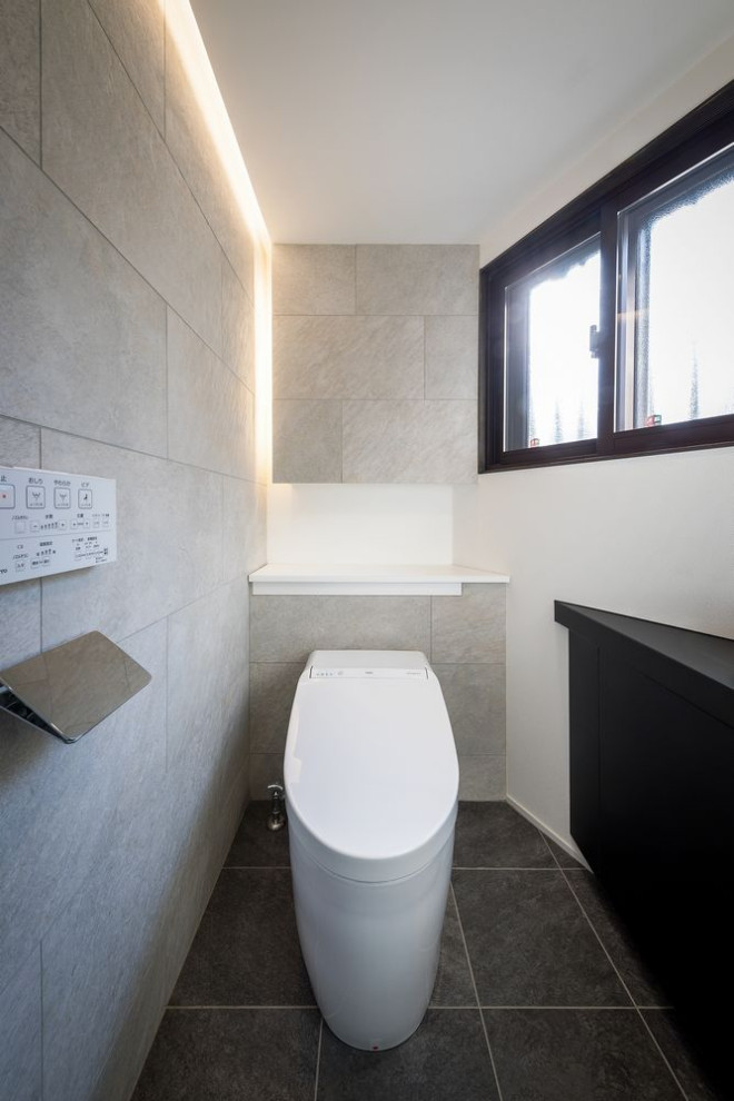 Идея дизайна: большой туалет в стиле модернизм с фасадами с утопленной филенкой, черными фасадами, унитазом-моноблоком, белой плиткой, керамической плиткой, белыми стенами, полом из керамической плитки, настольной раковиной, серым полом, черной столешницей, встроенной тумбой и потолком с обоями