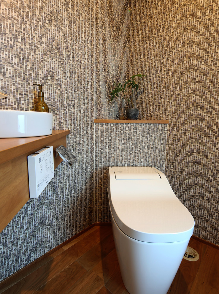 Moderne Gästetoilette mit bunten Wänden, braunem Holzboden, Aufsatzwaschbecken, Waschtisch aus Holz, braunem Boden und brauner Waschtischplatte in Sonstige