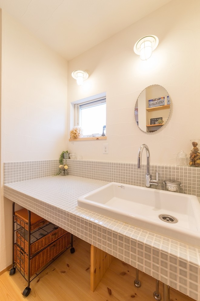 他の地域にあるアジアンスタイルのおしゃれなトイレ・洗面所 (白い壁、無垢フローリング、オーバーカウンターシンク、タイルの洗面台、茶色い床) の写真