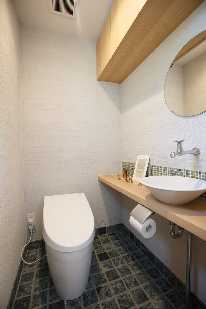 Inspiration pour un WC et toilettes asiatique avec un mur blanc, une vasque, un plan de toilette en bois, un sol gris et un plan de toilette beige.