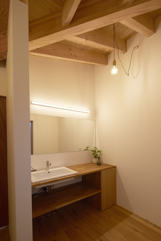 Inspiration pour un WC et toilettes nordique avec un carrelage blanc, un mur blanc, un sol en bois brun, un plan vasque, un plan de toilette en bois, un plan de toilette blanc et un sol marron.