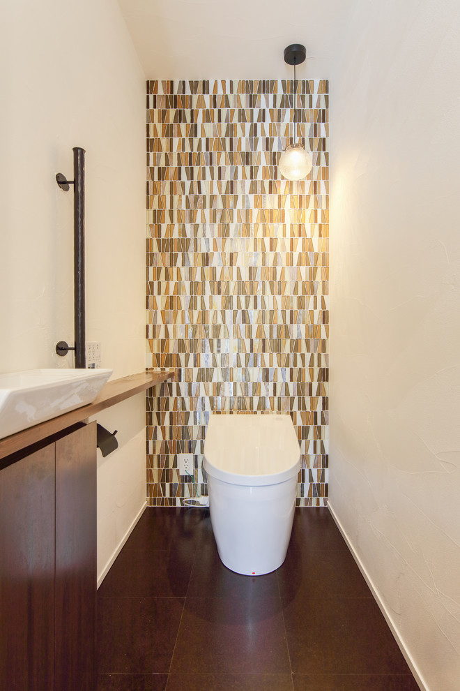 На фото: туалет среднего размера в восточном стиле с белыми стенами, настольной раковиной, столешницей из дерева и коричневым полом с