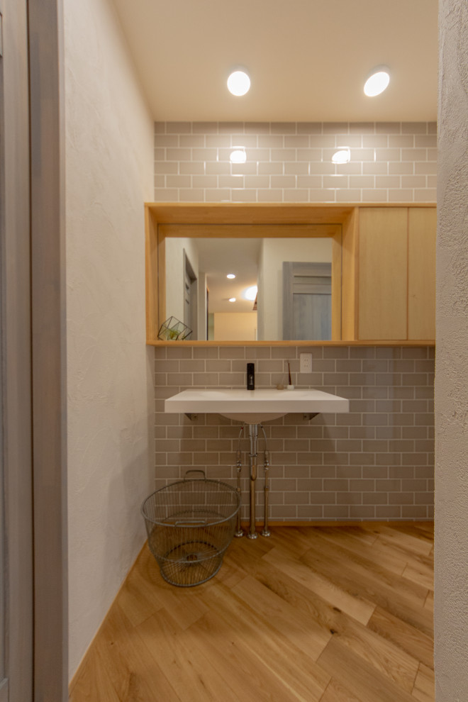 Esempio di un bagno di servizio moderno con ante bianche, piastrelle grigie, pareti grigie, pavimento in legno massello medio e mobile bagno sospeso