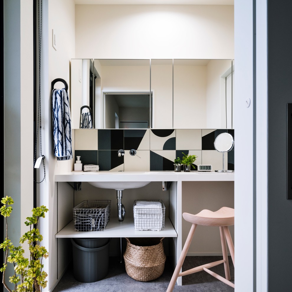 Diseño de aseo minimalista con armarios abiertos, baldosas y/o azulejos blancos, baldosas y/o azulejos negros, paredes blancas, lavabo integrado, suelo gris y encimeras blancas