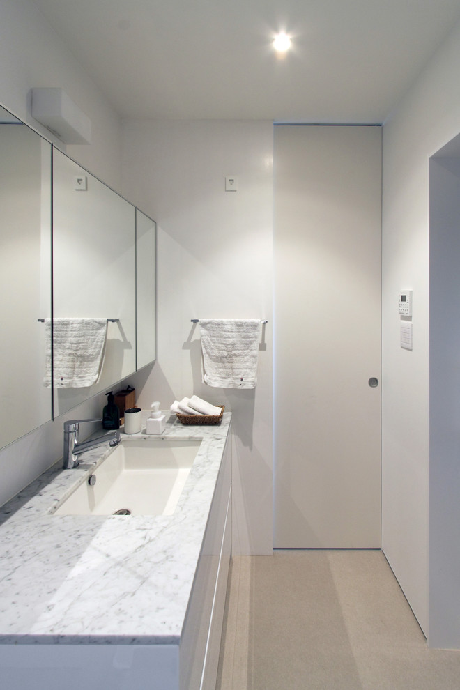 東京都下にある北欧スタイルのおしゃれなトイレ・洗面所 (シェーカースタイル扉のキャビネット、白いキャビネット、白い壁、人工大理石カウンター、白い床) の写真