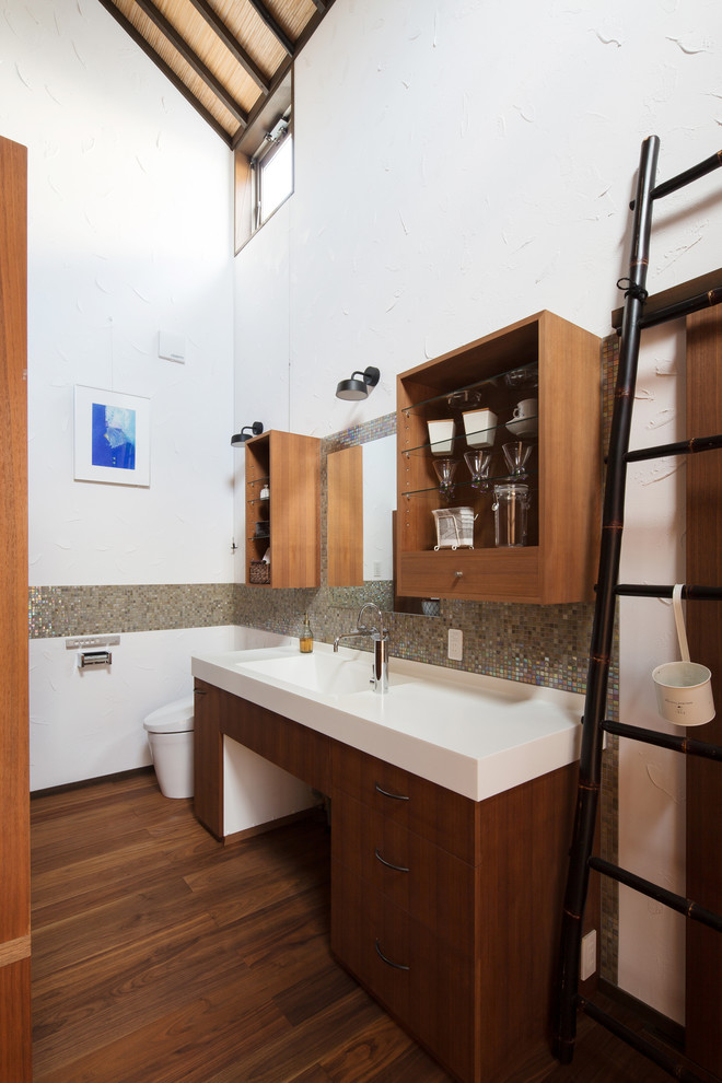 Bild på ett orientaliskt toalett, med vita väggar, mörkt trägolv och brunt golv
