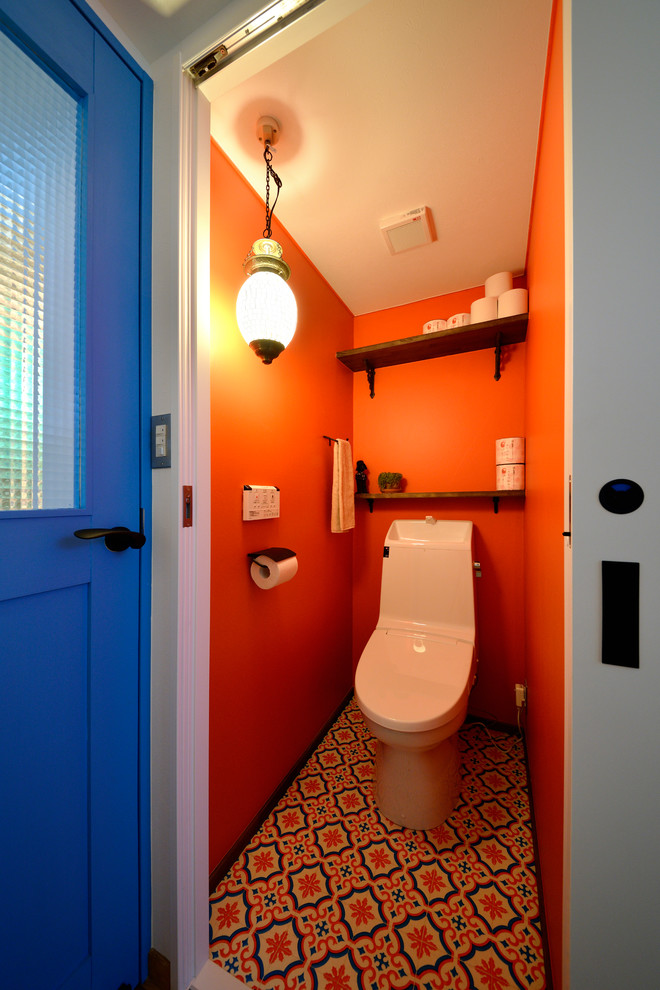 Bild på ett minimalistiskt toalett, med öppna hyllor, orange väggar och flerfärgat golv