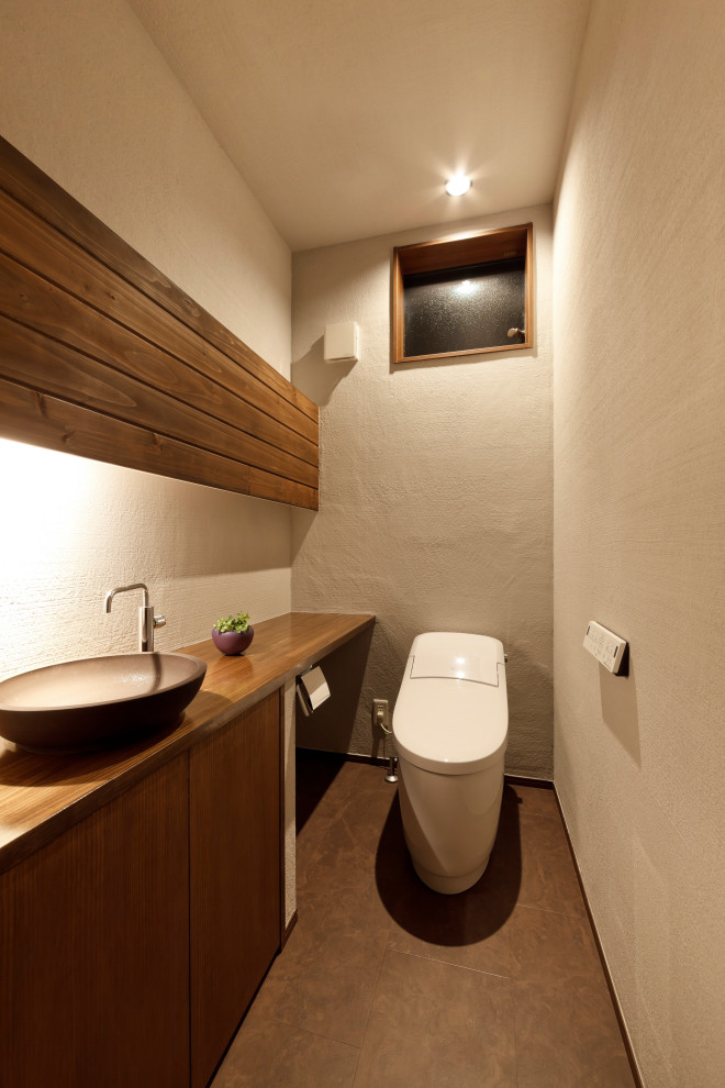 Cette photo montre un WC et toilettes avec des portes de placard marrons, WC à poser, un mur gris, un lavabo posé, un plan de toilette en bois, un sol marron, un plan de toilette marron, un plafond en lambris de bois et du lambris de bois.