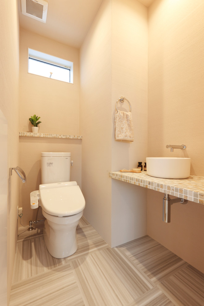 Moderne Gästetoilette mit beiger Wandfarbe, grauem Boden, farbigen Fliesen und bunter Waschtischplatte in Sonstige