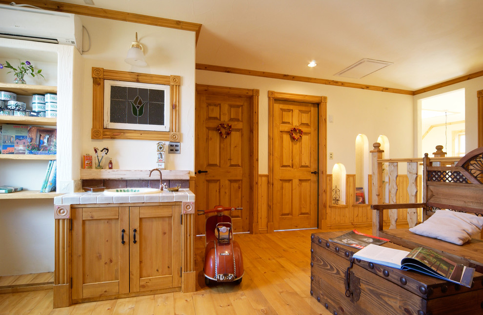 Klassische Gästetoilette mit braunen Schränken, weißer Wandfarbe, hellem Holzboden, Einbauwaschbecken, gefliestem Waschtisch und braunem Boden in Sonstige