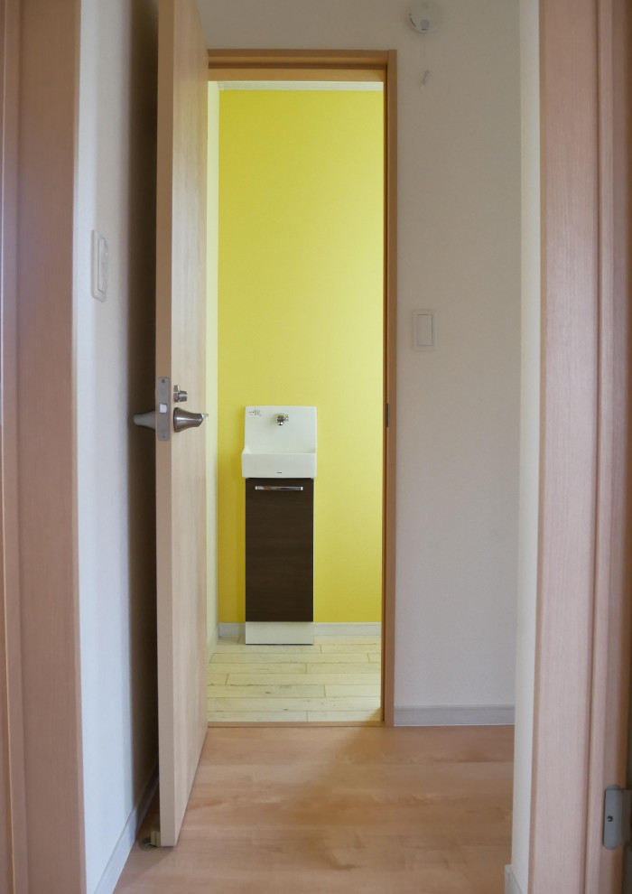 Diseño de aseo mediterráneo pequeño con puertas de armario marrones, paredes amarillas, suelo vinílico, lavabo suspendido, encimera de madera, suelo blanco y encimeras marrones